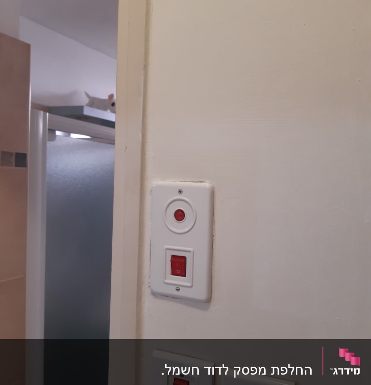 מתגי חשמל על קיר לבן עם כפתור אדום